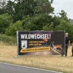Vereinsmitglieder stellen Schild "Wildwechsel!" auf