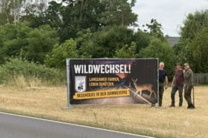 Vereinsmitglieder stellen Schild "Wildwechsel!" auf